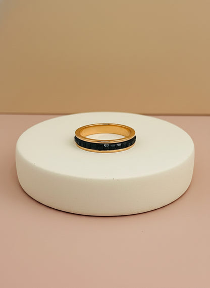 Rose Gold ring with black stones on a white box with beige background