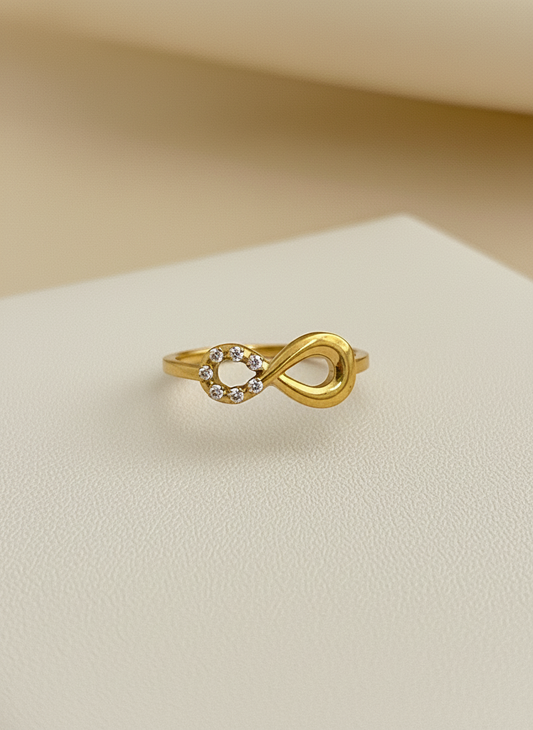 Gold infinity ring with small diamonds on a beige surface