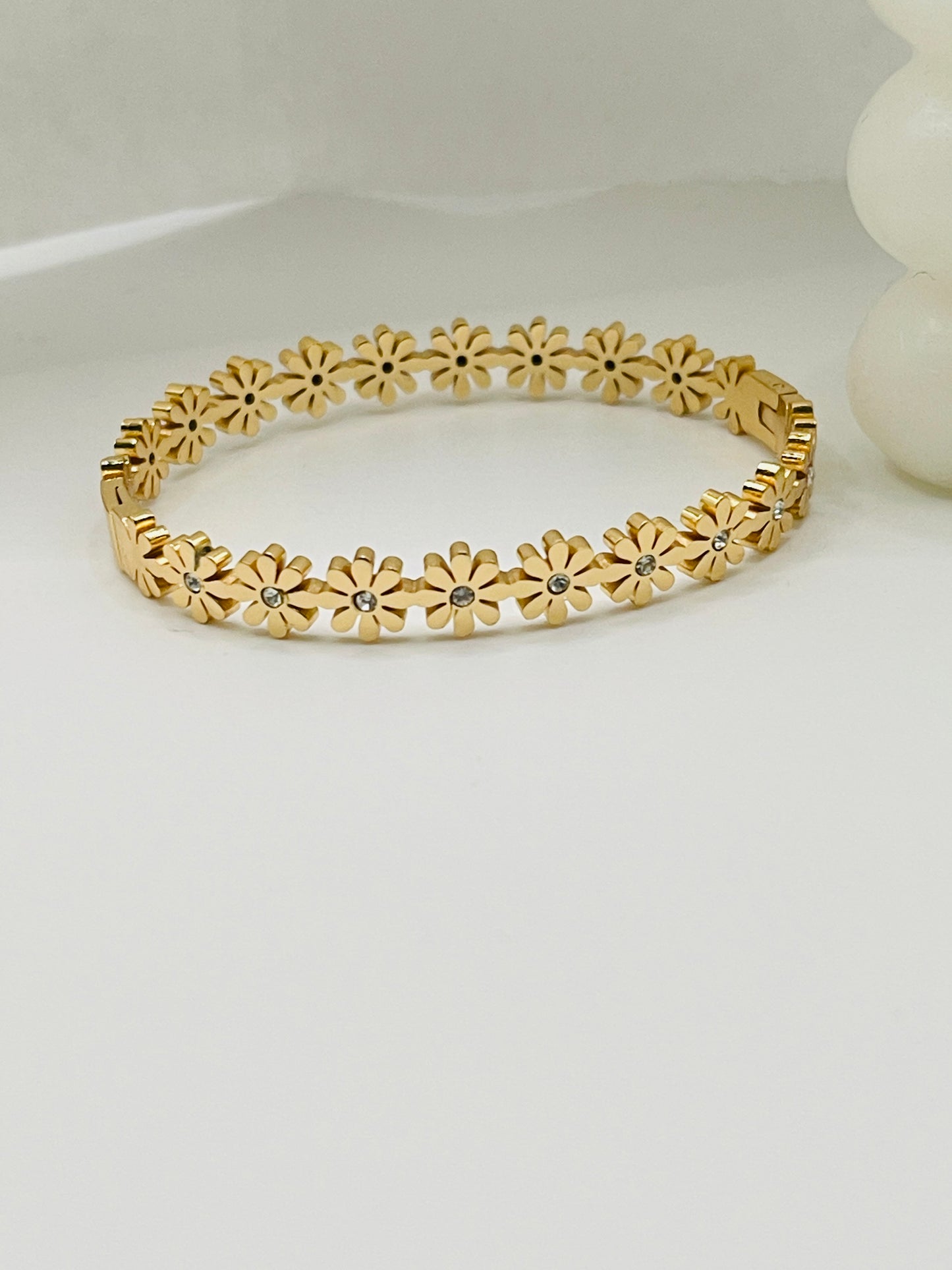 Gold bracelet with floral designs on a white surface