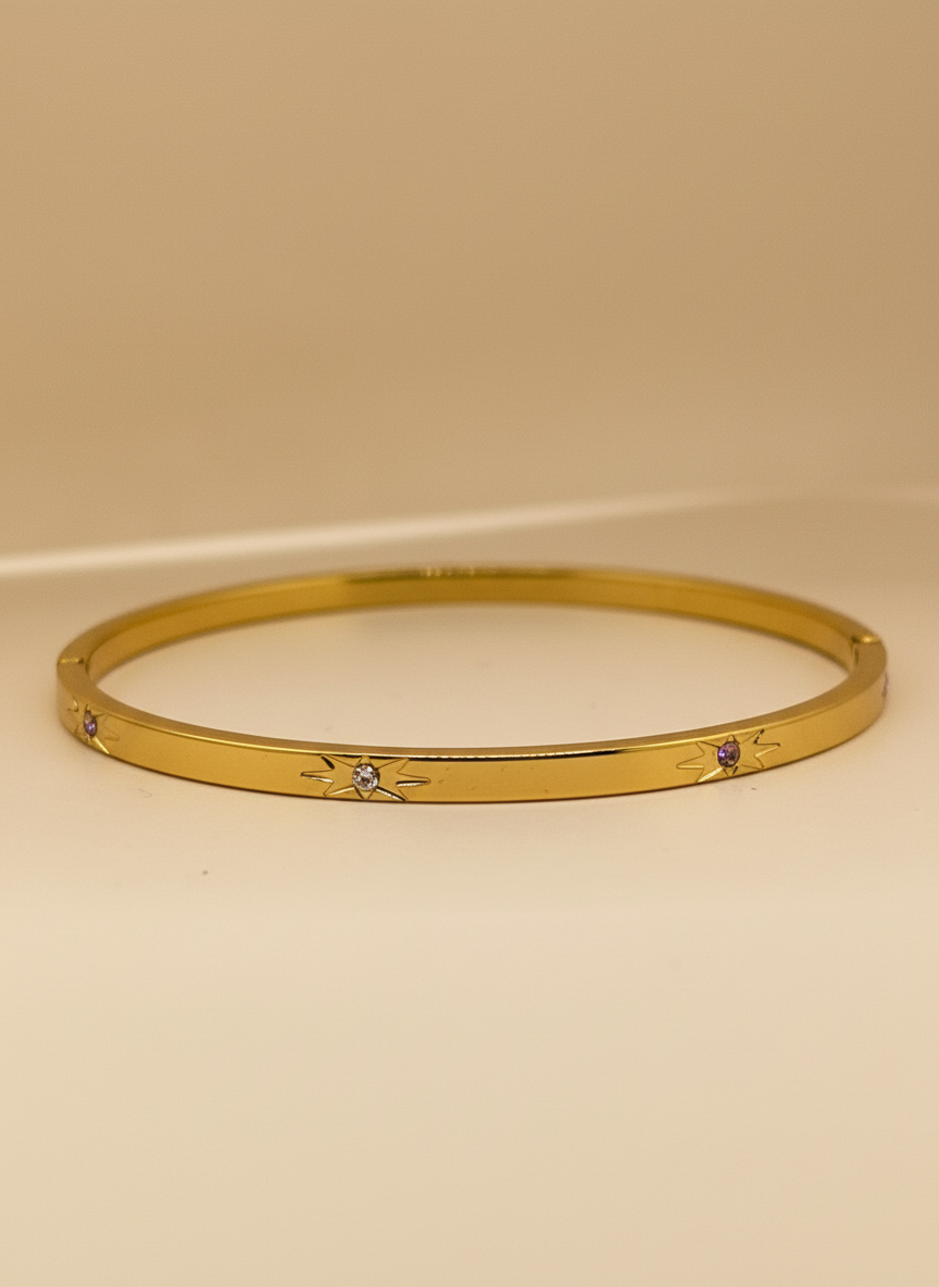 Gold bracelet with small stones on a beige background