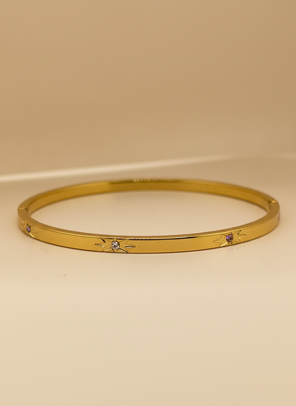 Gold bracelet with small stones on a beige background