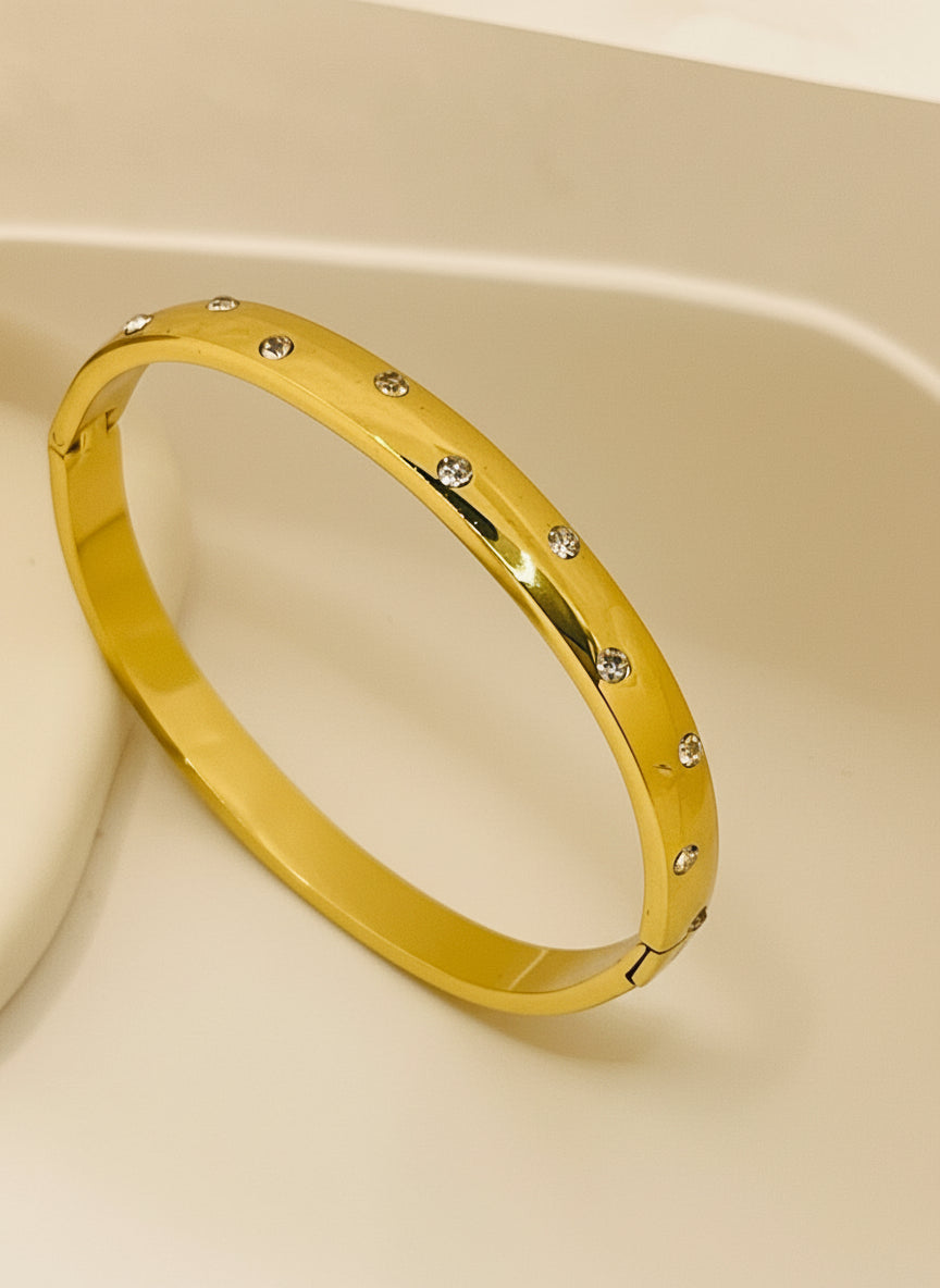 Gold bracelet with small stones on a white background