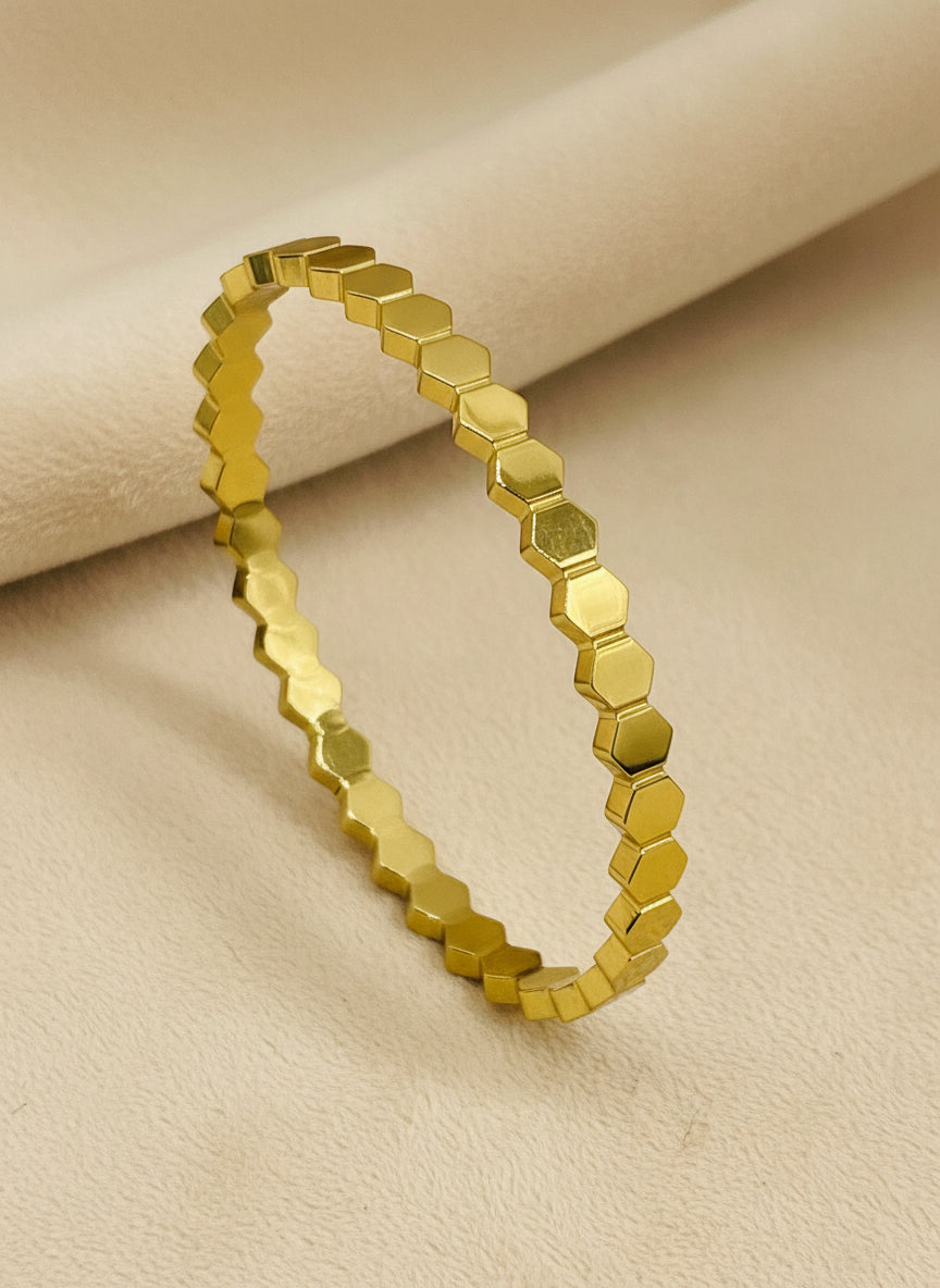 Gold hexagonal bangle on a white background
