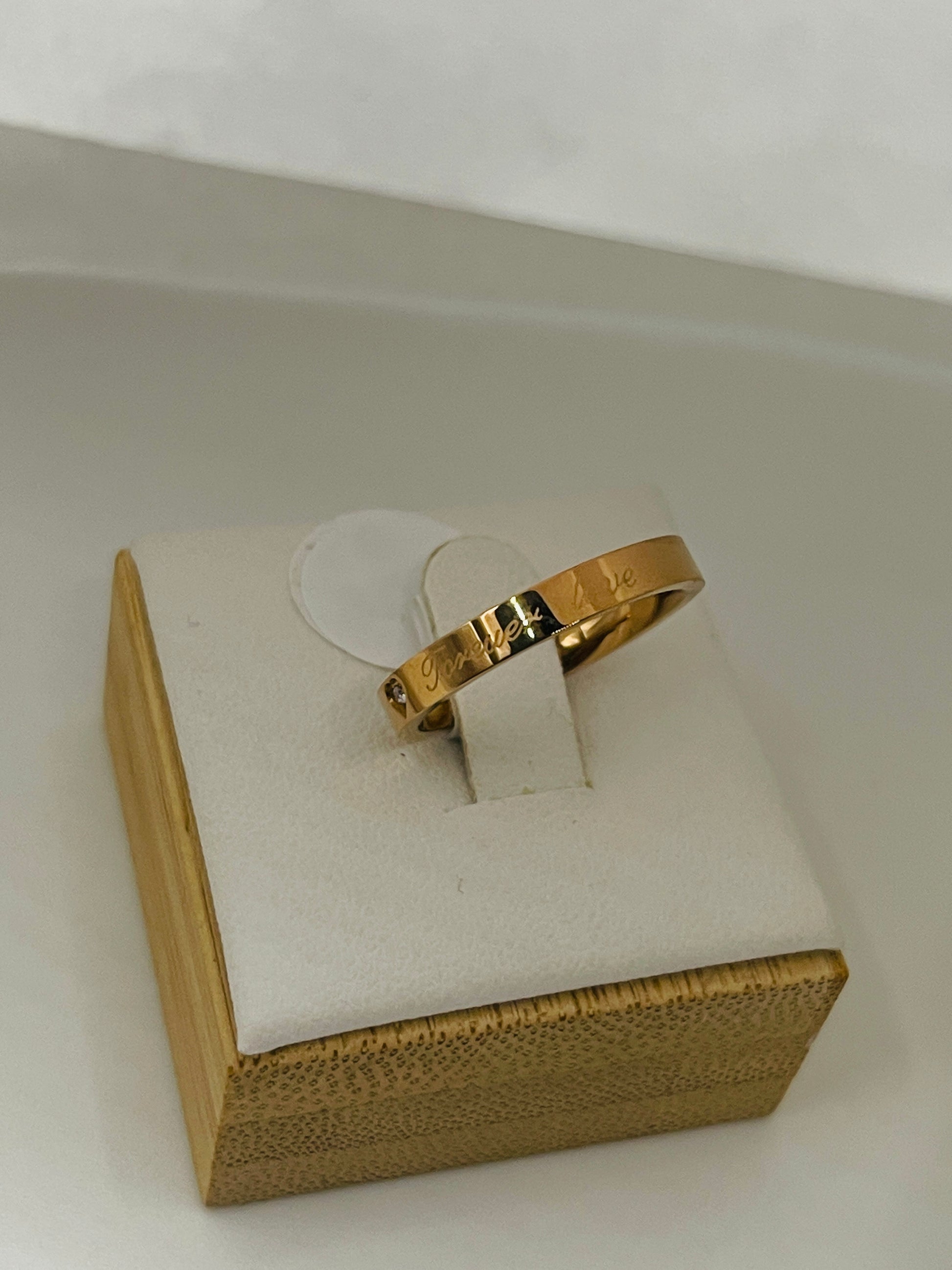Rose Gold ring on a white stand with a beige box