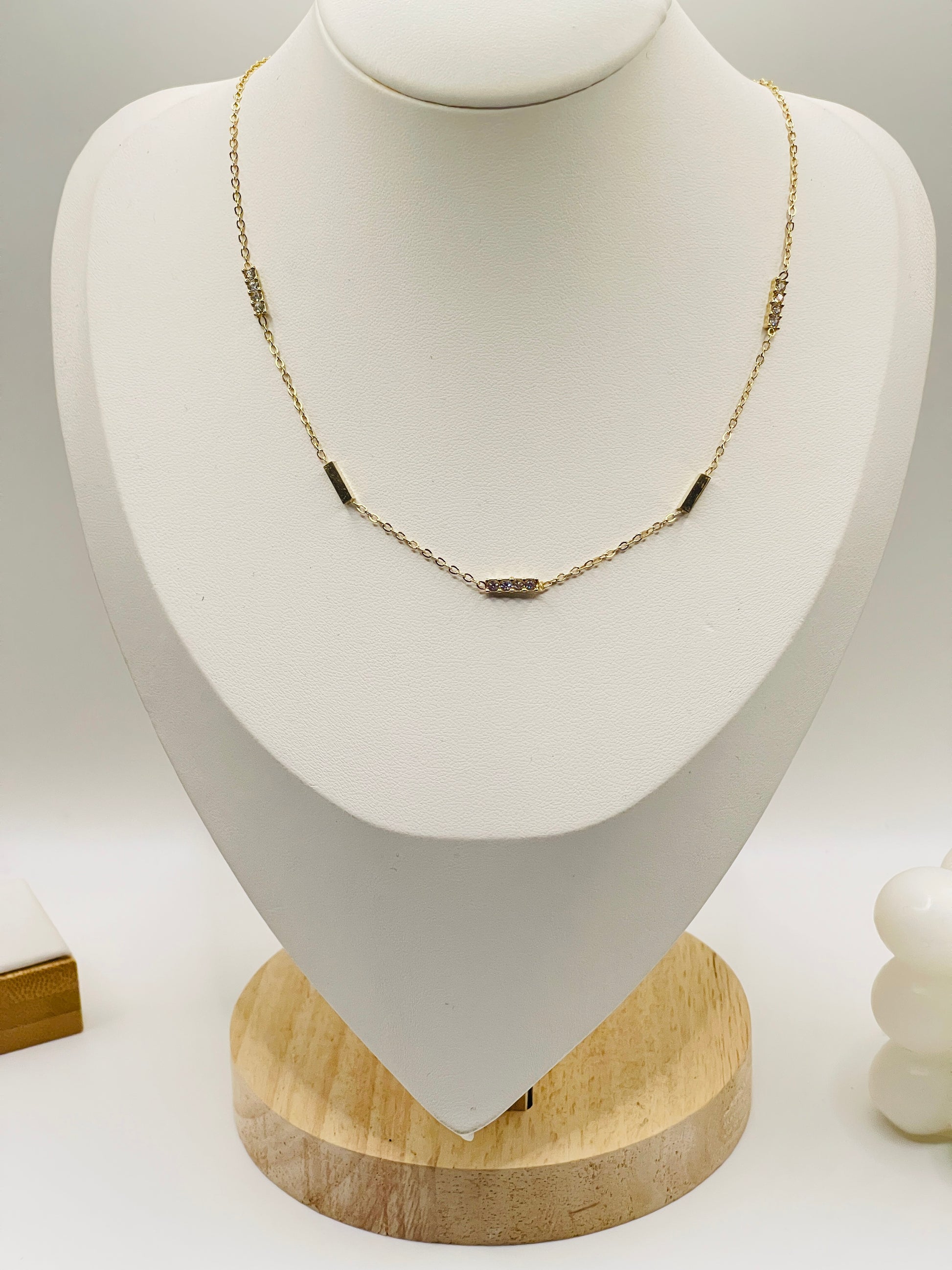 Necklace with black beads on a white mannequin bust with a wooden base.