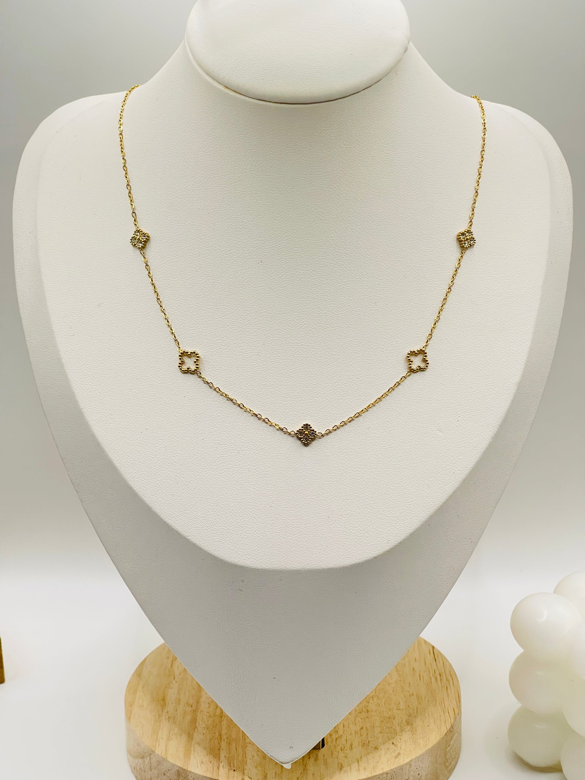 Gold necklace on a white mannequin bust with a wooden base