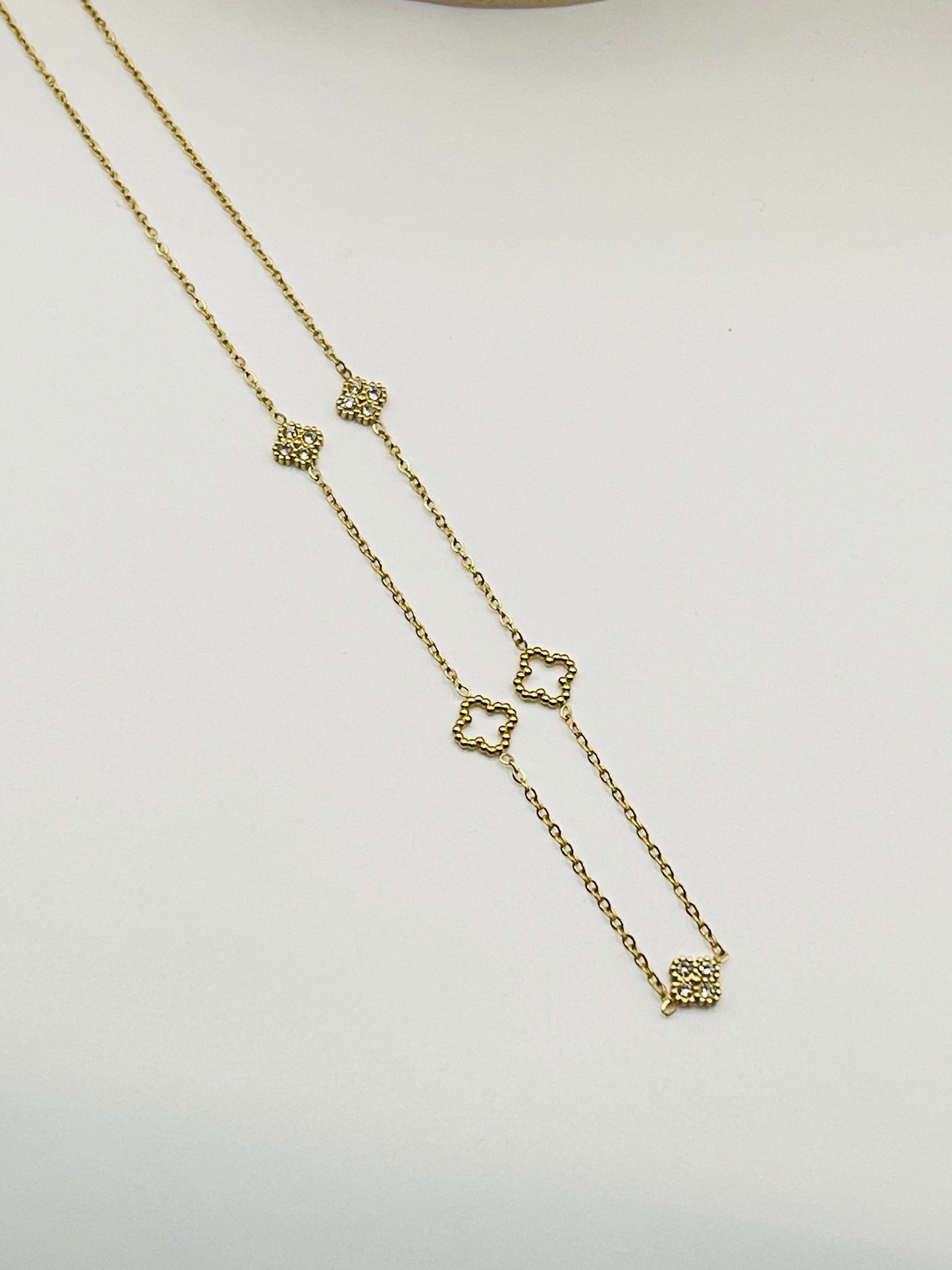 Gold necklace with heart-shaped charms on a light gray background