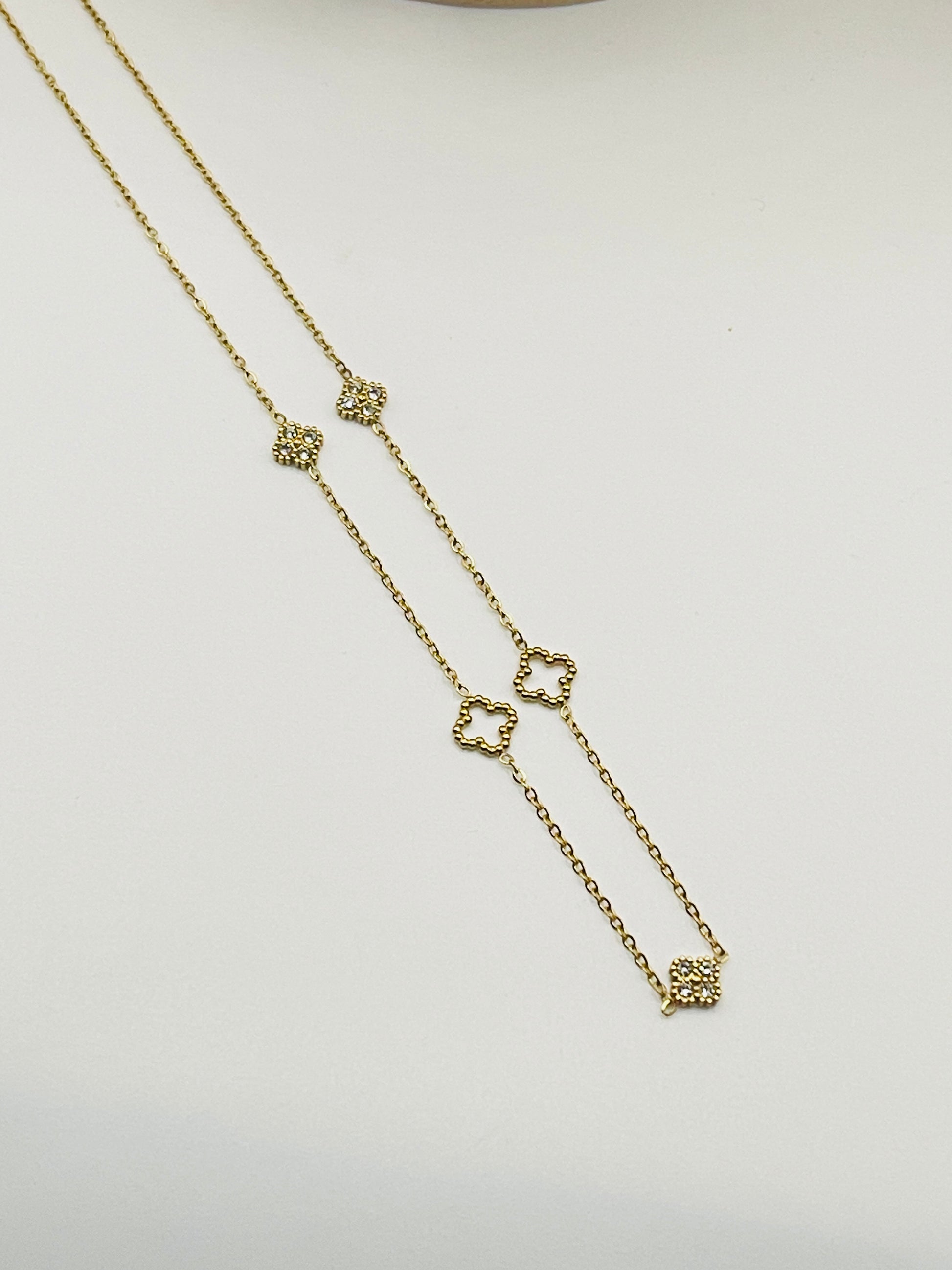 Gold necklace with heart-shaped charms on a light gray background