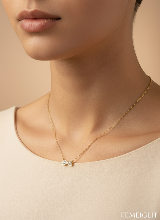Gold necklace with a pendant on a model against a beige background, featuring the brand 'FEMEIGLIT'.