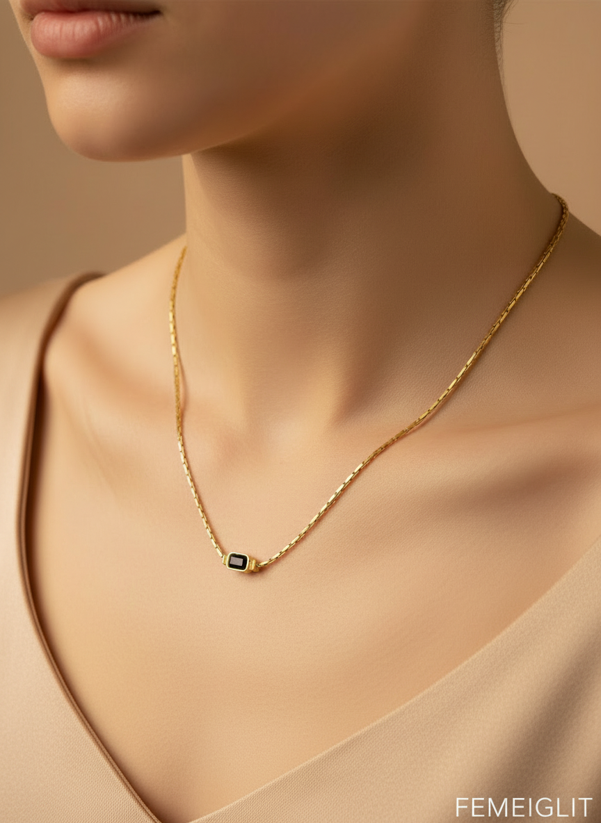 Gold necklace with a dark blue gemstone on a mannequin bust.