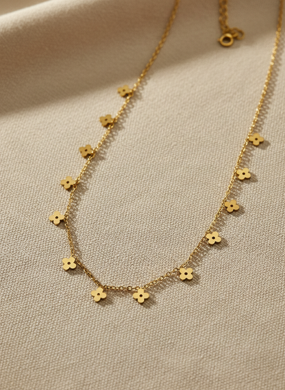 Gold necklace with flower-shaped pendants on a beige fabric background