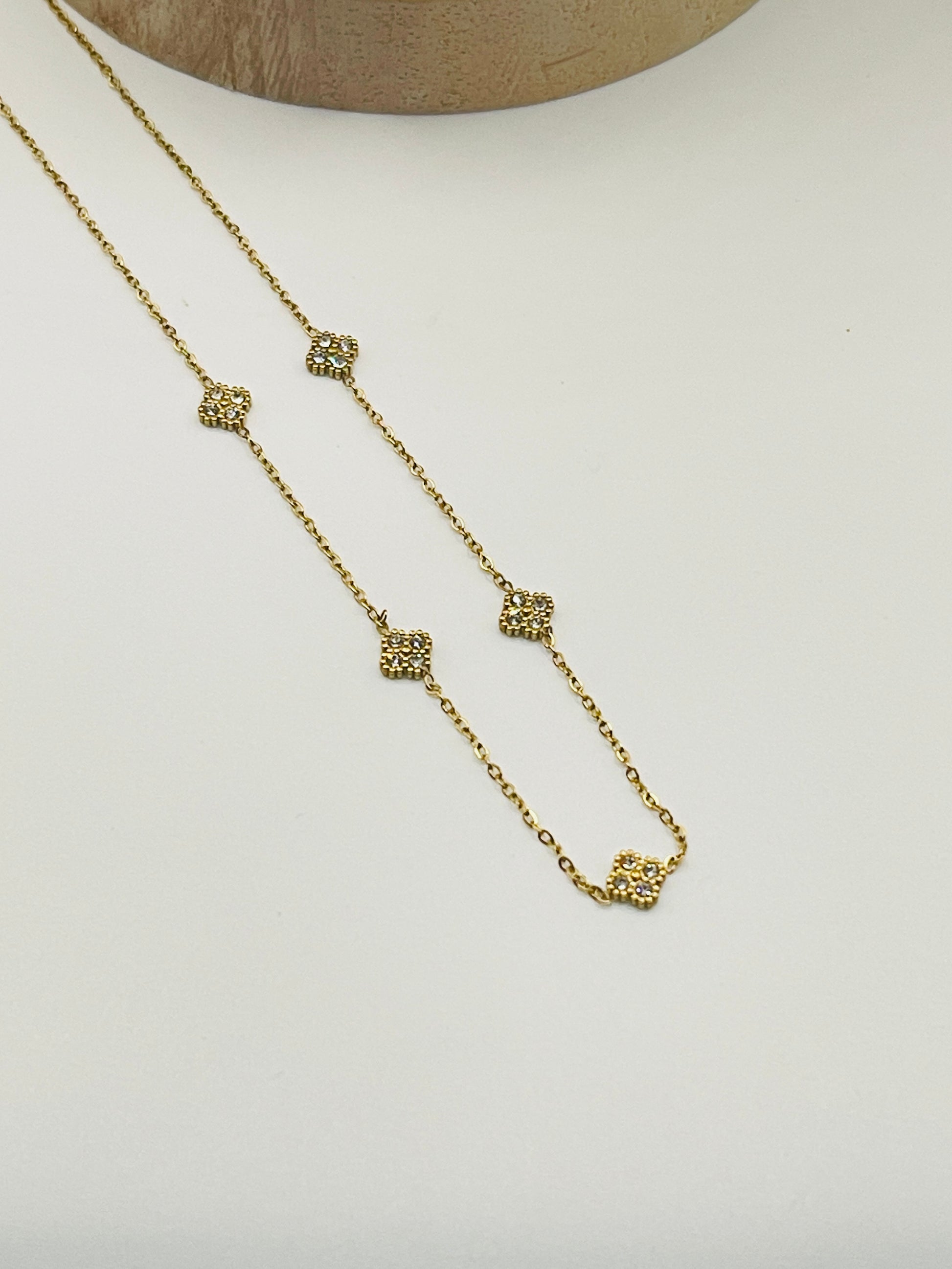 Gold necklace with diamond-like pendants on a light gray background