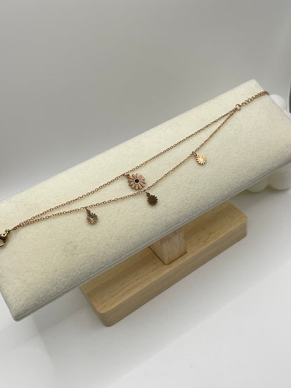 Rose gold with floral pendants on a beige stand against a white background