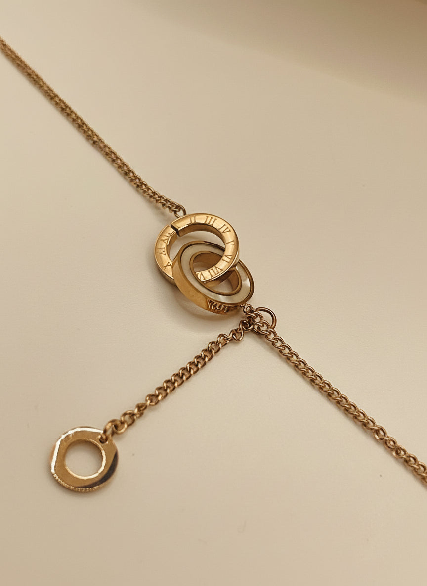 Rose gold chain bracelet 
with interlocking rings on a light gray background