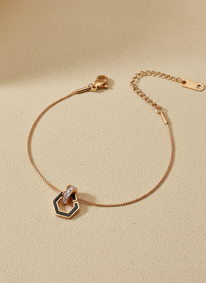 Rose gold bracelet with a hexagonal clasp on a beige background