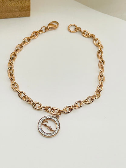 Rose gold bracelet with a circular charm on a white background