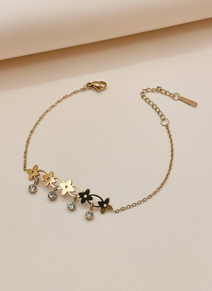 Rose gold bracelet with floral designs and small stones on a white surface.