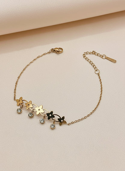 Rose gold bracelet with floral designs and small stones on a white surface.