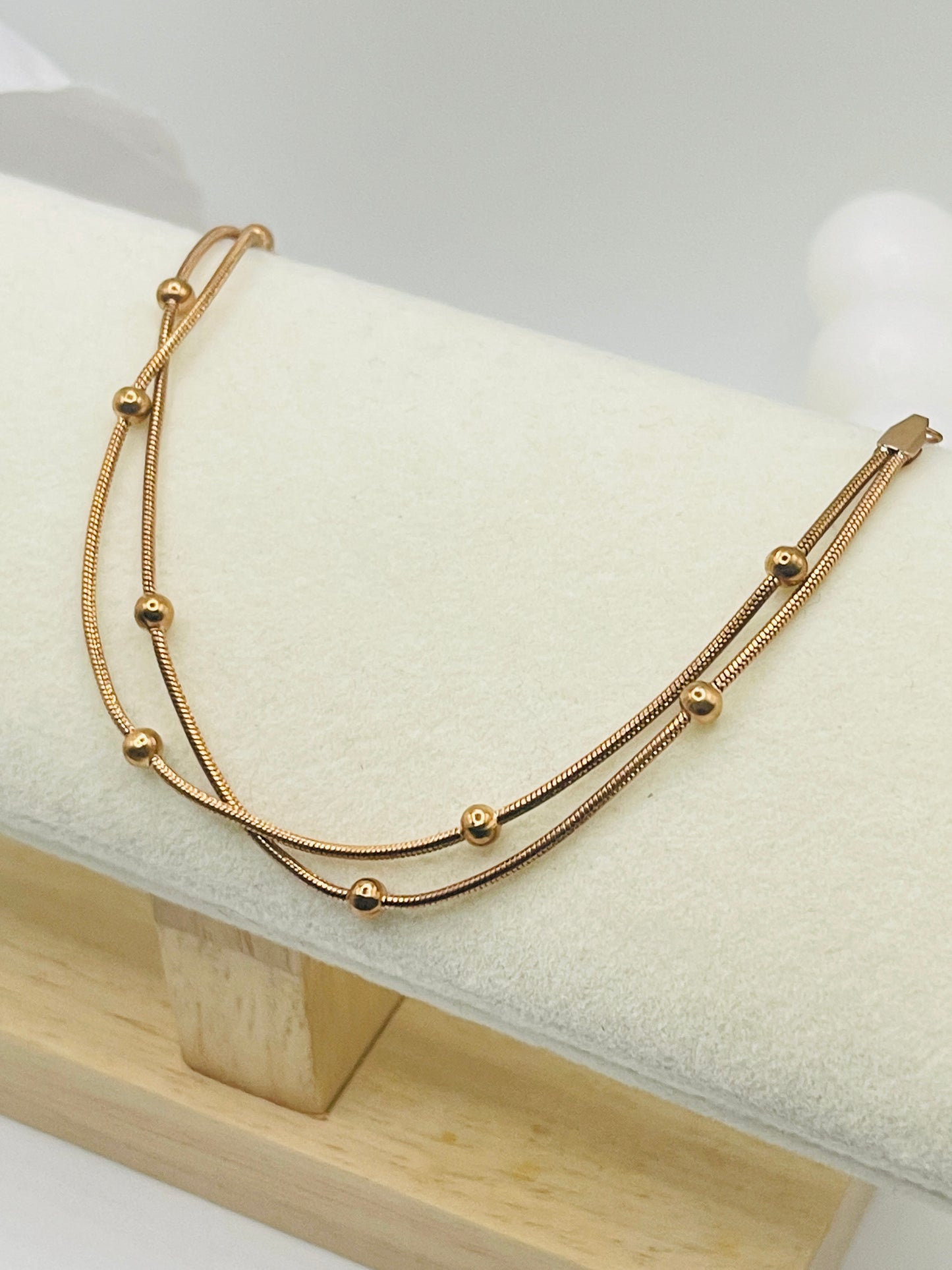 Rose Gold bracelet on a white cushion with a light wooden base