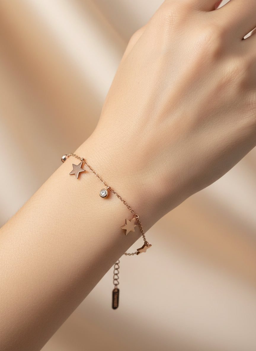 Rose gold bracelet with star charms on a light background