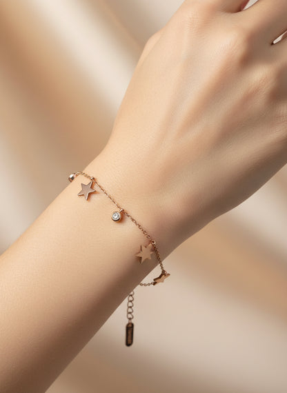 Rose gold bracelet with star charms on a light background