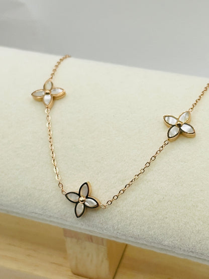 Gold hand chain with flower -shaped pendants on a white cushion