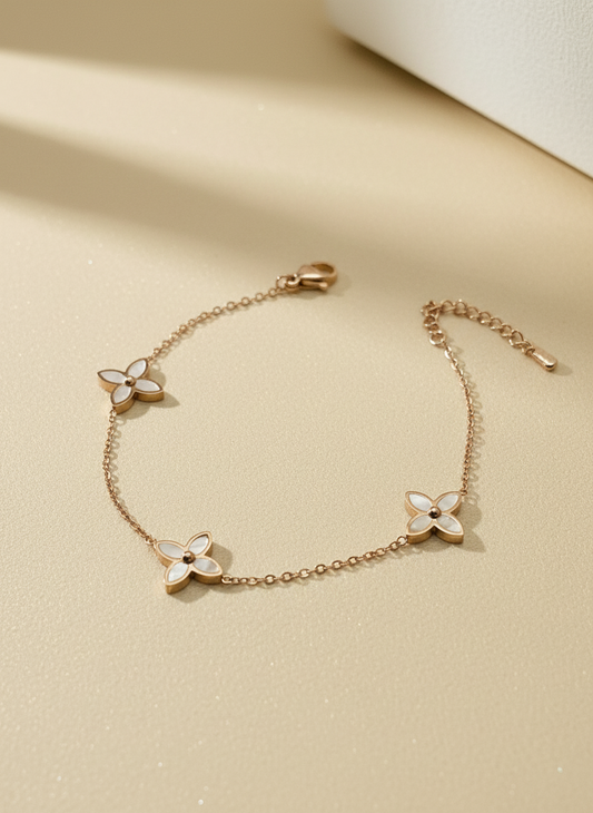 Rose gold bracelet with floral charms on a beige background