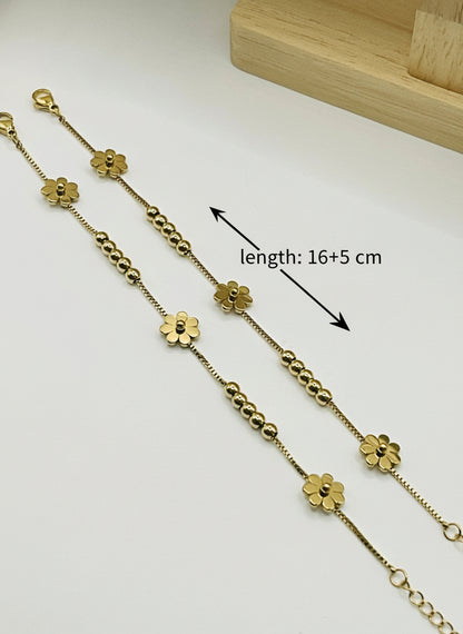 Gold kids anklet with floral designs on a white surface