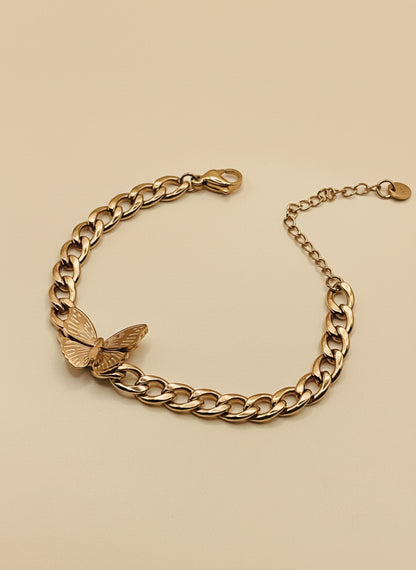 Rose Gold chain bracelet with a butterfly charm on a beige background