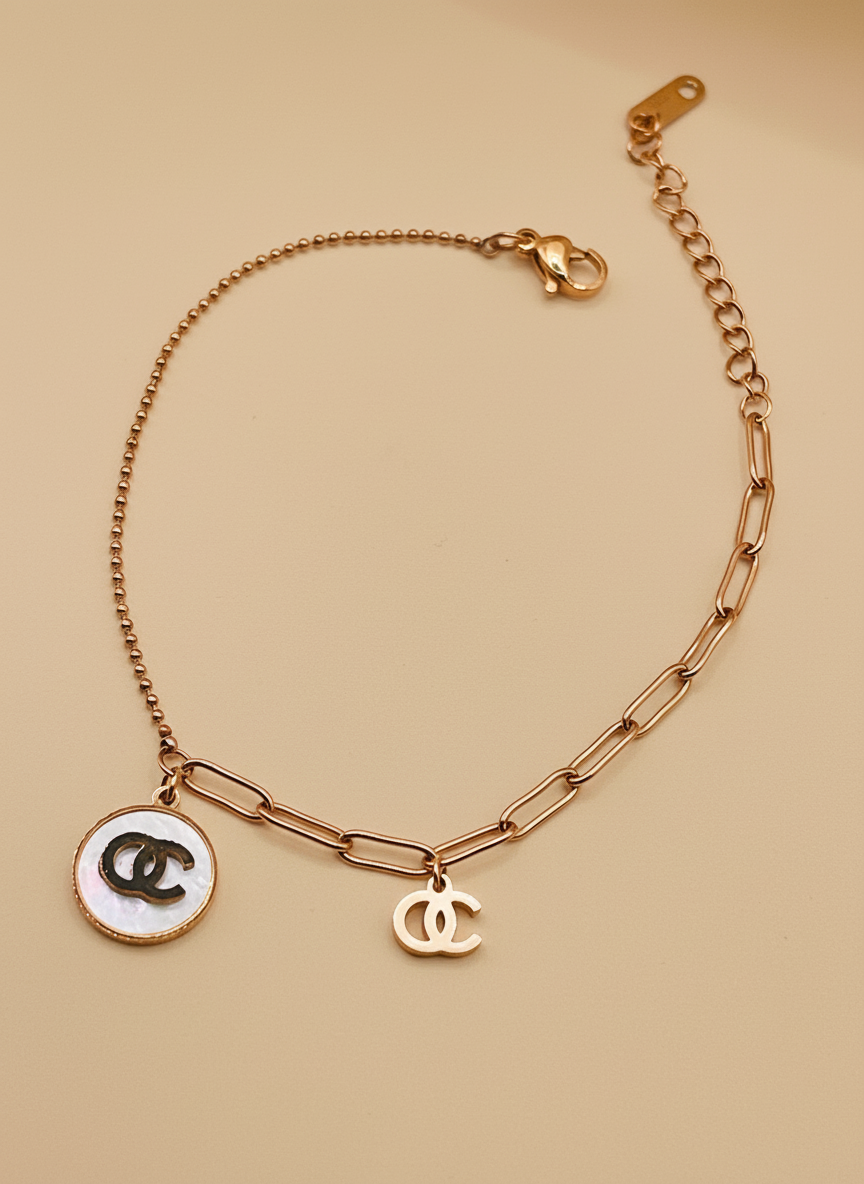 Rose Gold chain bracelet with CC logo charms on a beige background