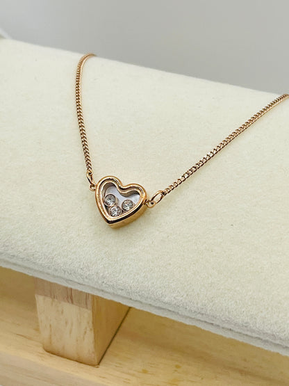 Rose Gold heart-shaped necklace with embedded stones on a white cushion