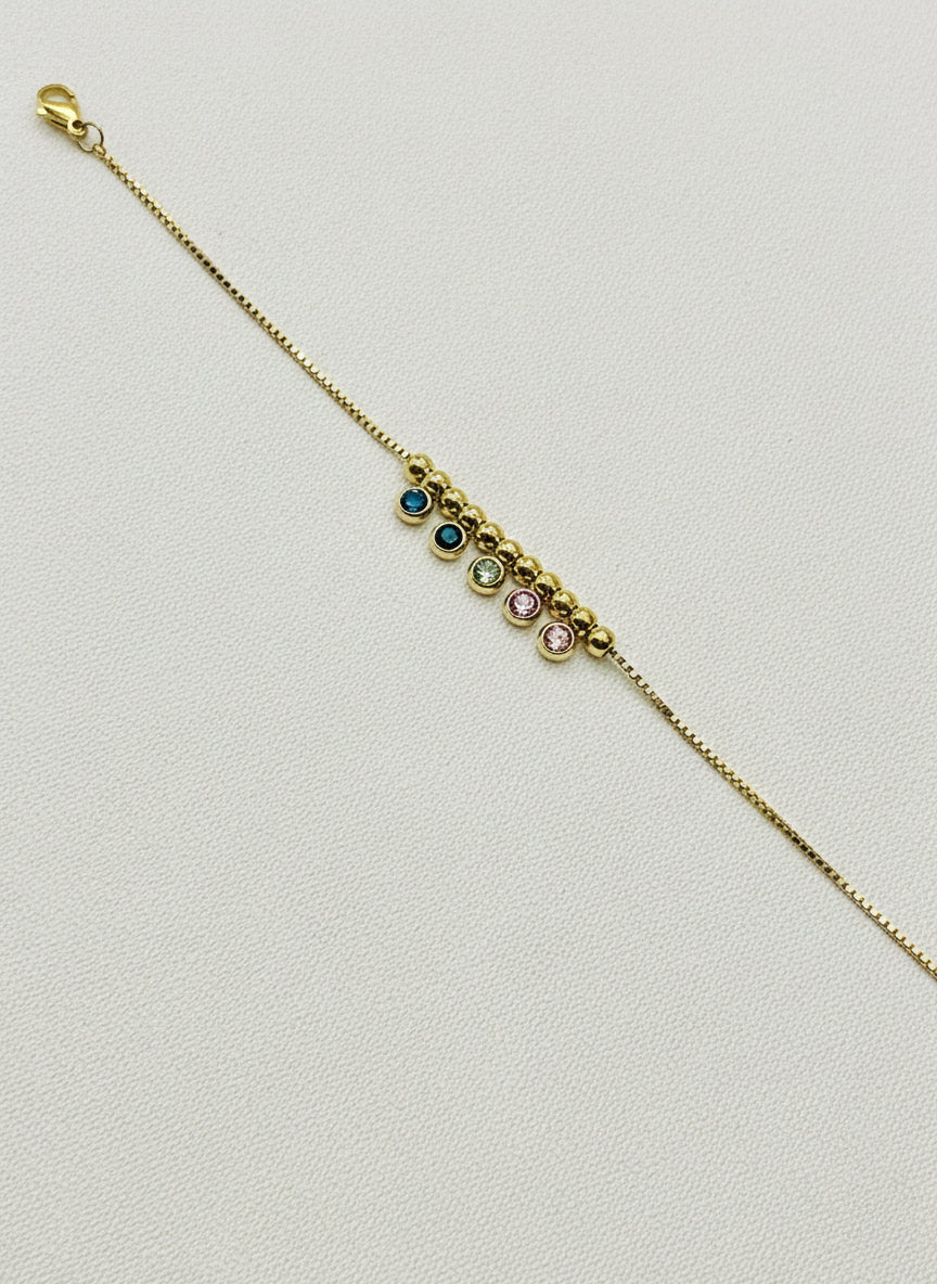 Gold bracelet with embedded stones on a white background
