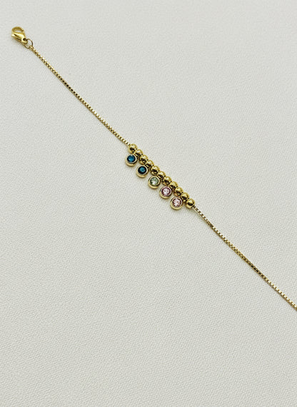 Gold bracelet with embedded stones on a white background