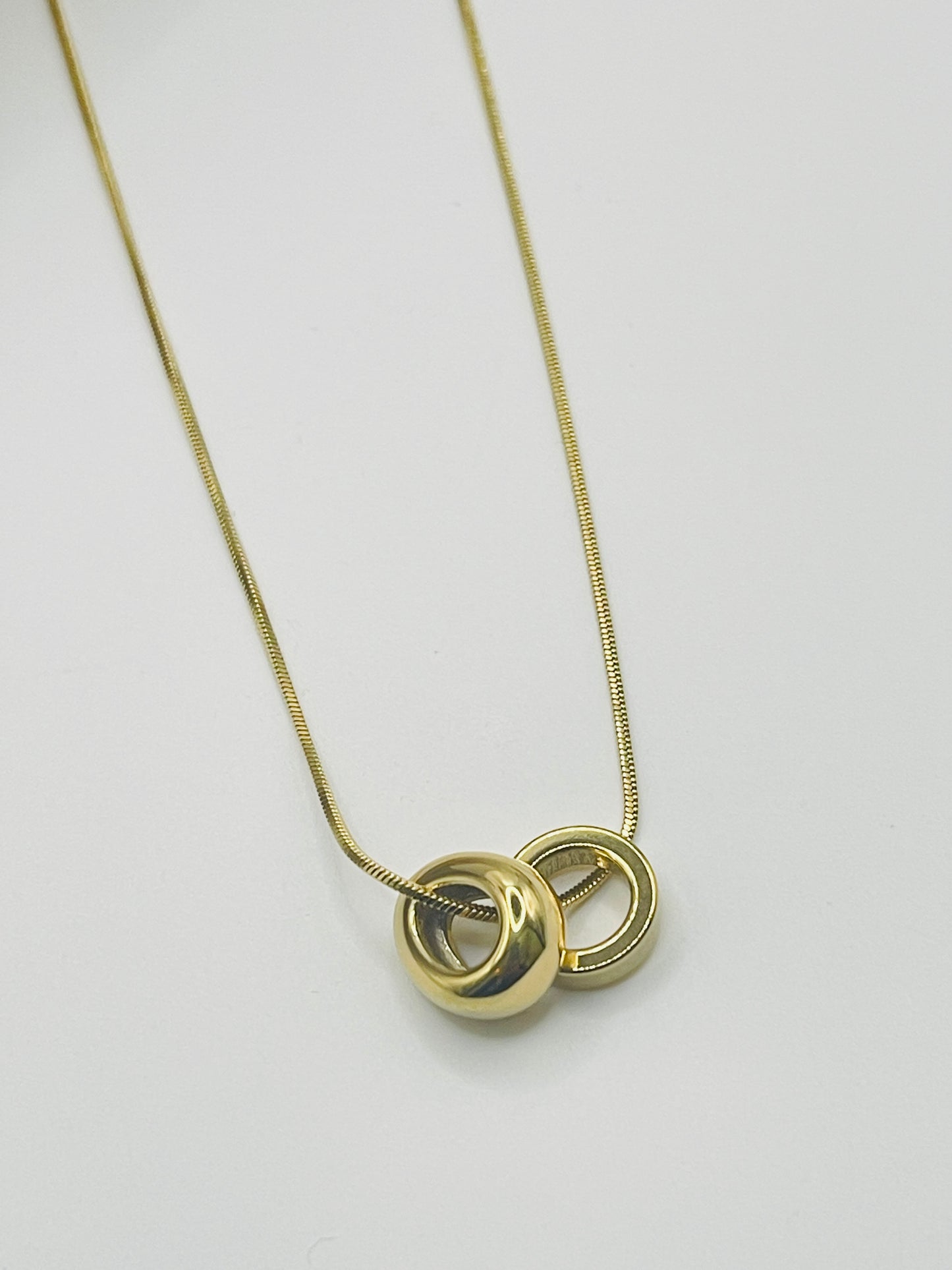 Gold necklace with a unique pendant on a light gray background