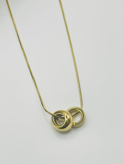 Gold necklace with a unique pendant on a light gray background