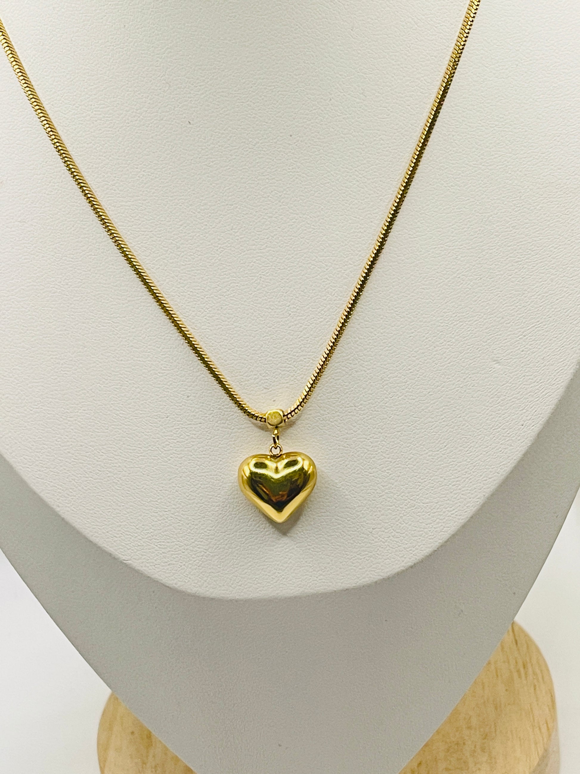 Gold heart-shaped pendant necklace on a mannequin bust.
