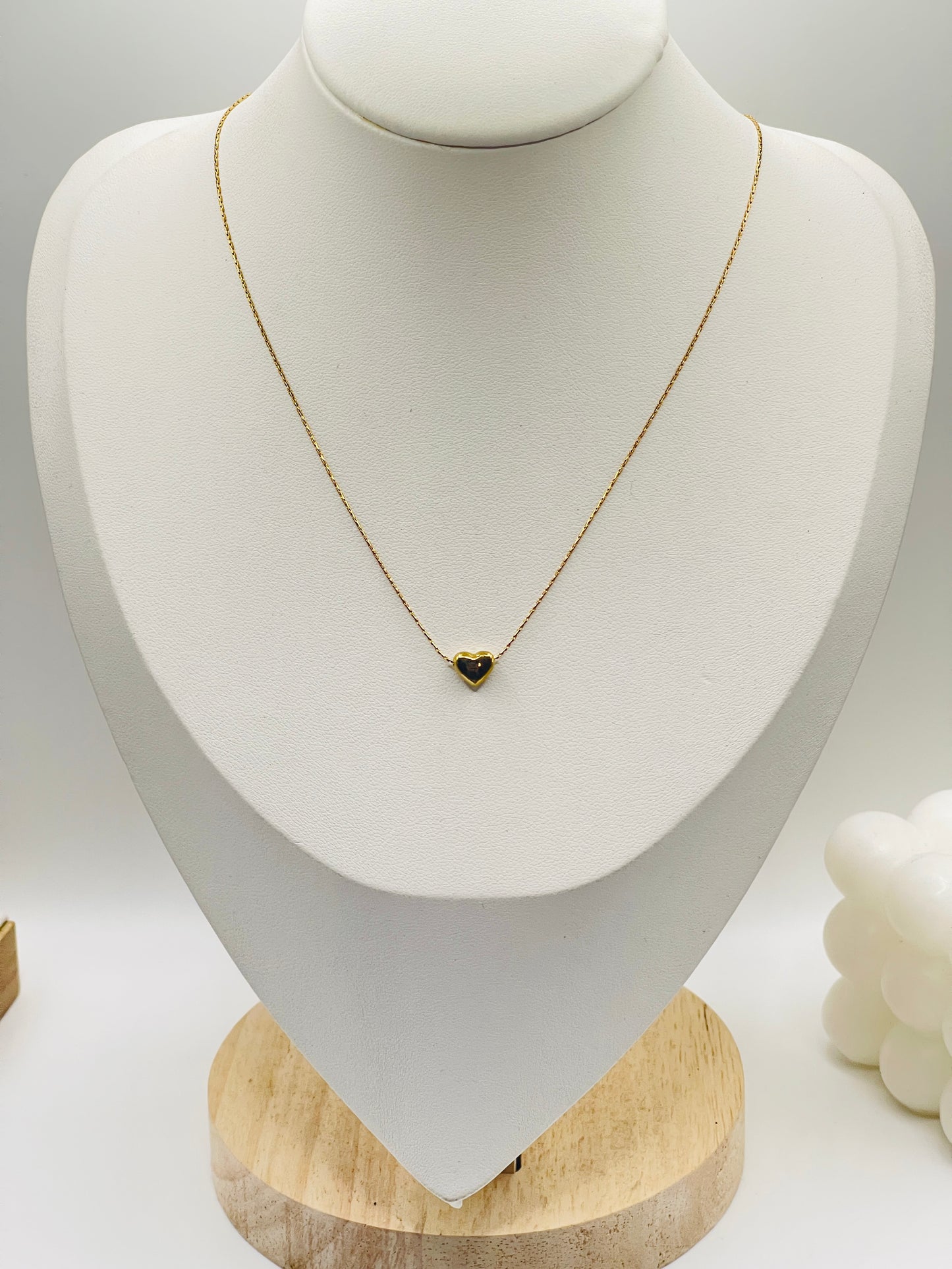 Gold necklace with a heart pendant on a white mannequin bust.