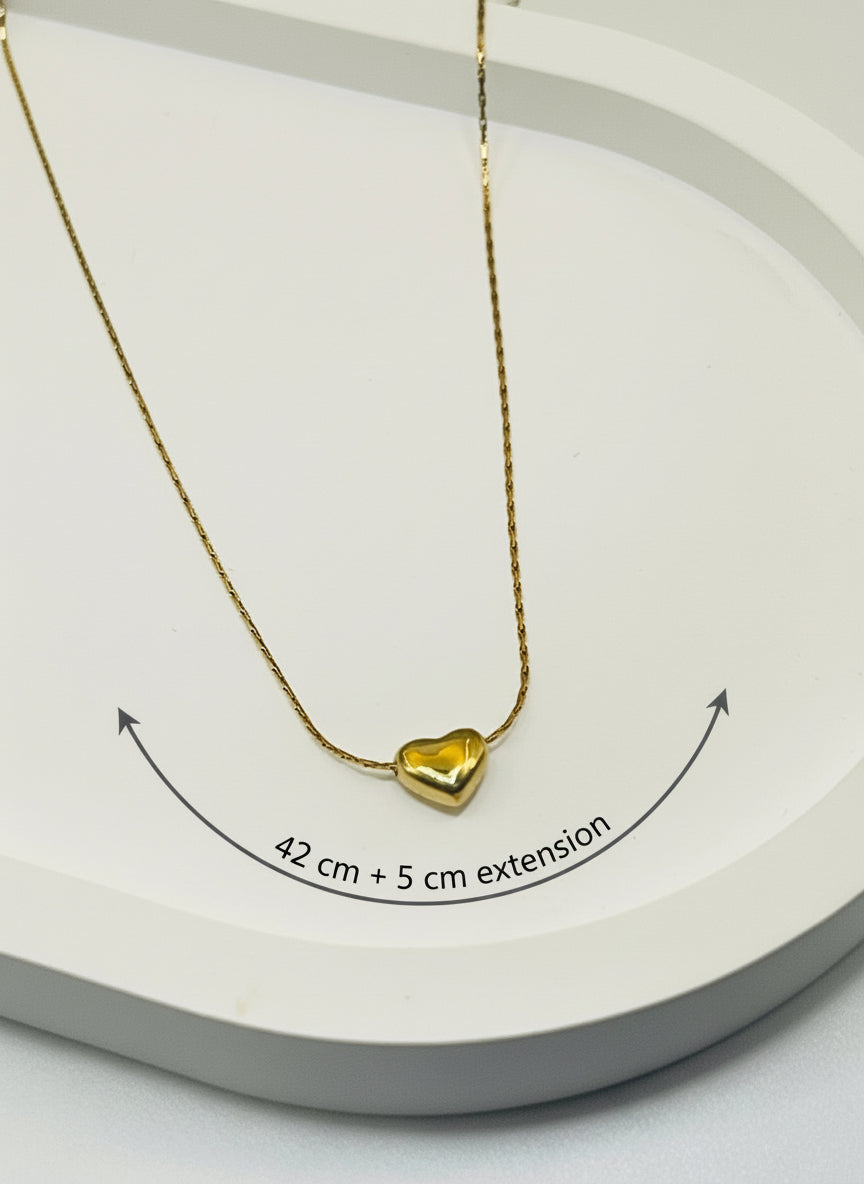 Gold heart-shaped necklace on a white surface