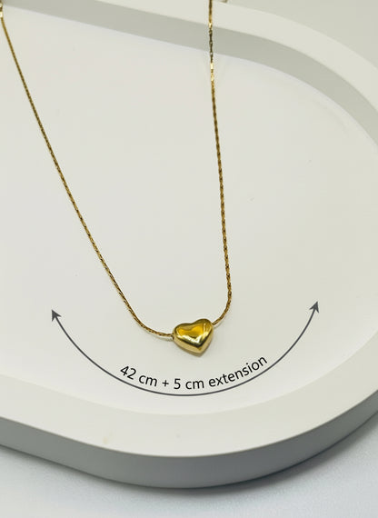 Gold heart-shaped necklace on a white surface