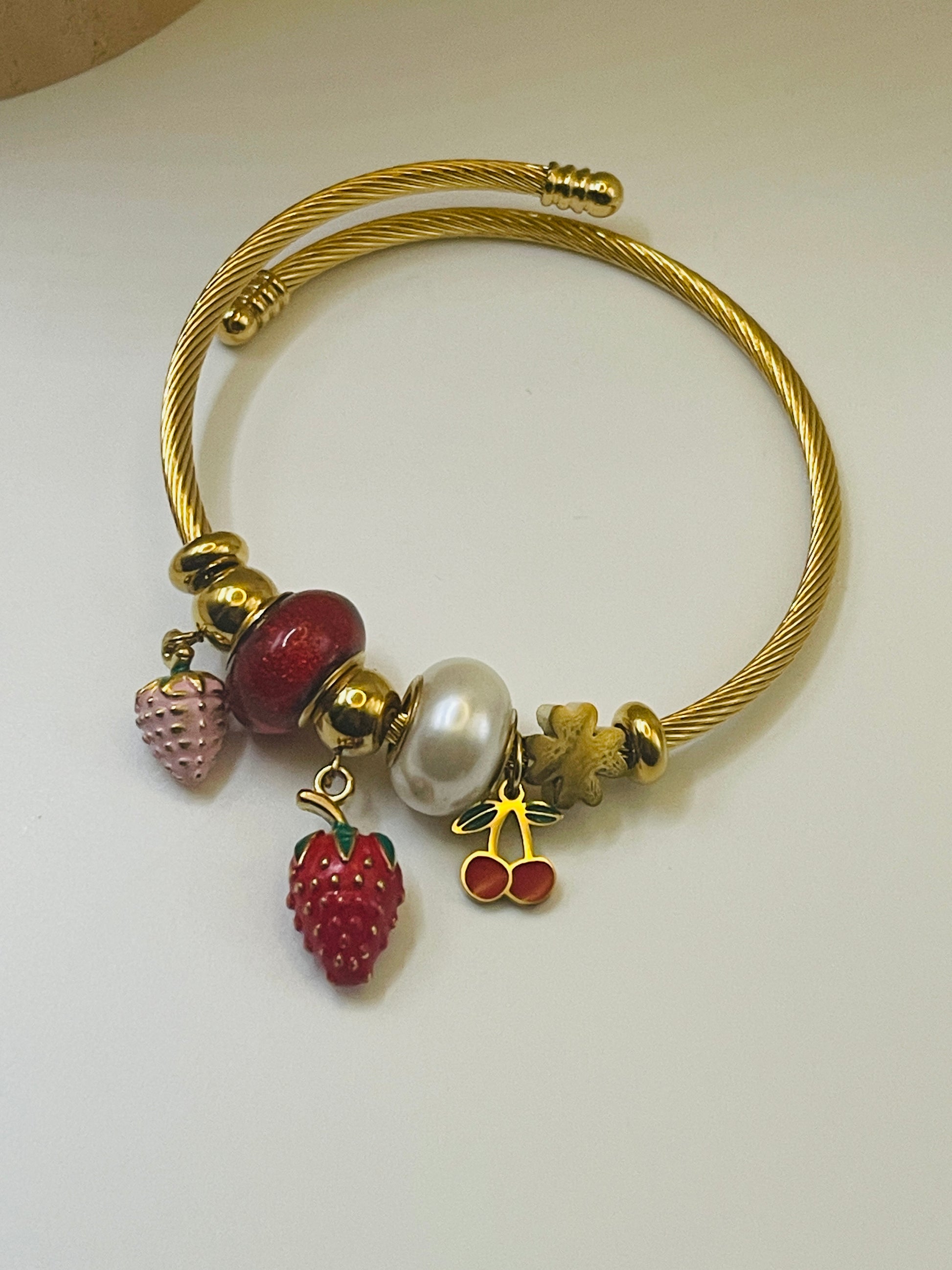 Gold bracelet with strawberry-shaped charms on a white background
