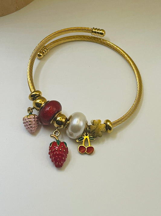 Gold bracelet with strawberry-shaped charms on a white background