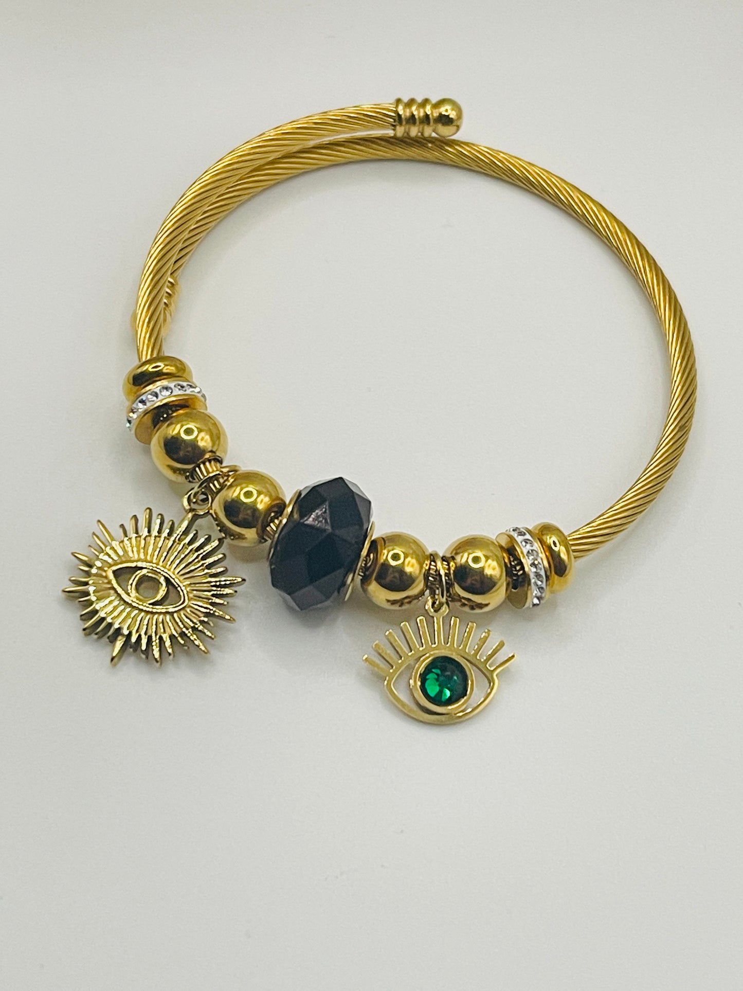 Gold bracelet with decorative beads and charms on a white background