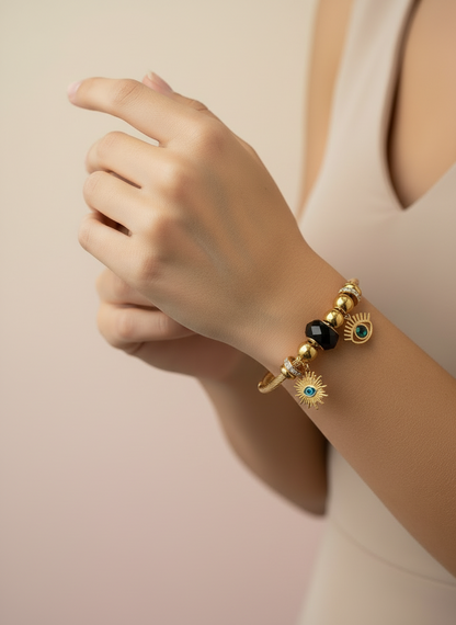 Gold bracelet with black and blue beads on a wrist against a beige background