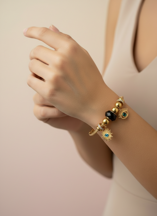 Gold bracelet with black and blue beads on a wrist against a beige background