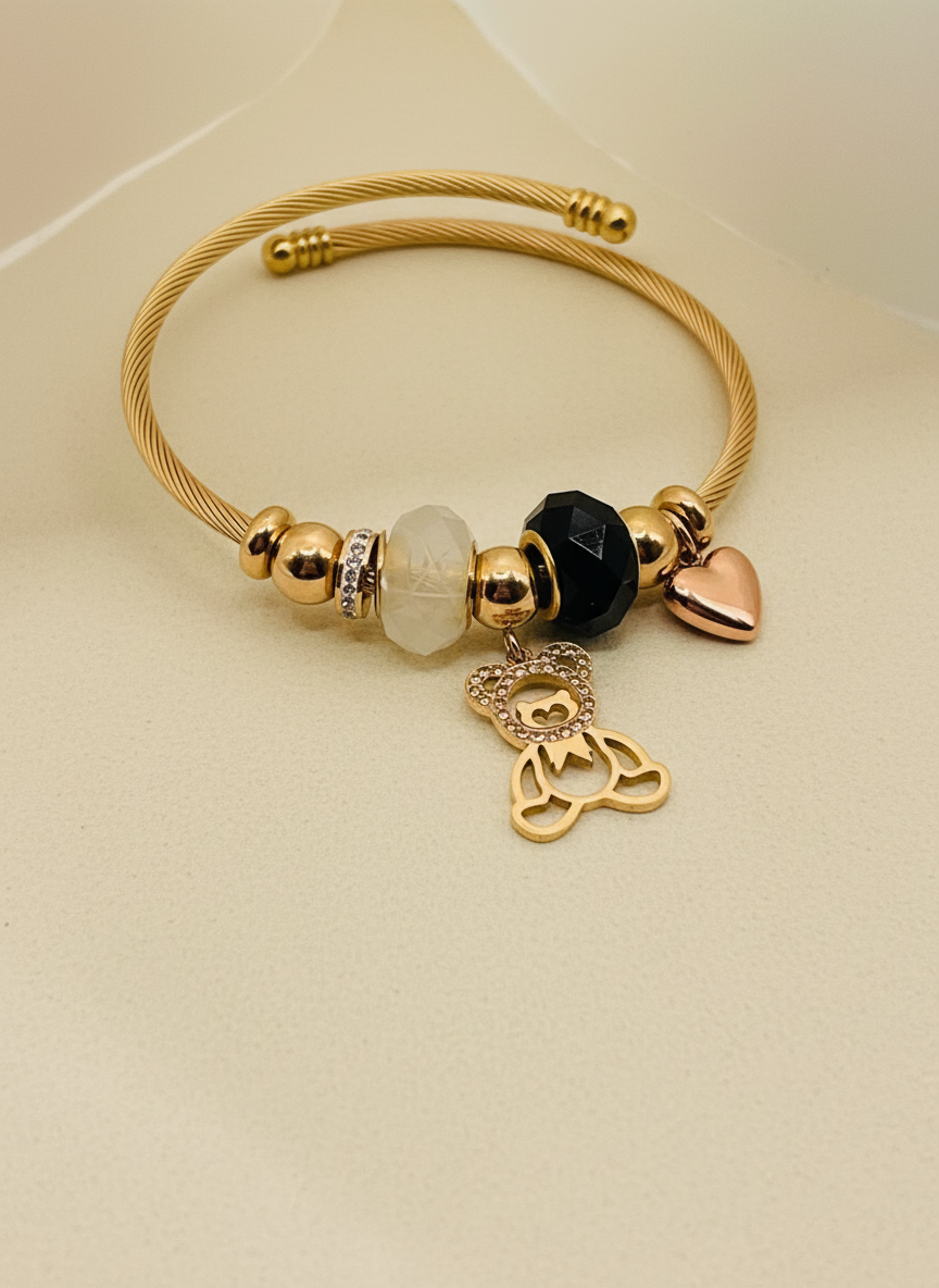Gold bracelet with various charms on a beige background