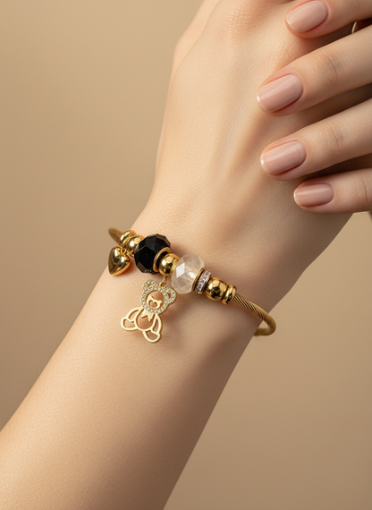 Gold bracelet with black and clear beads on a wrist against a beige background