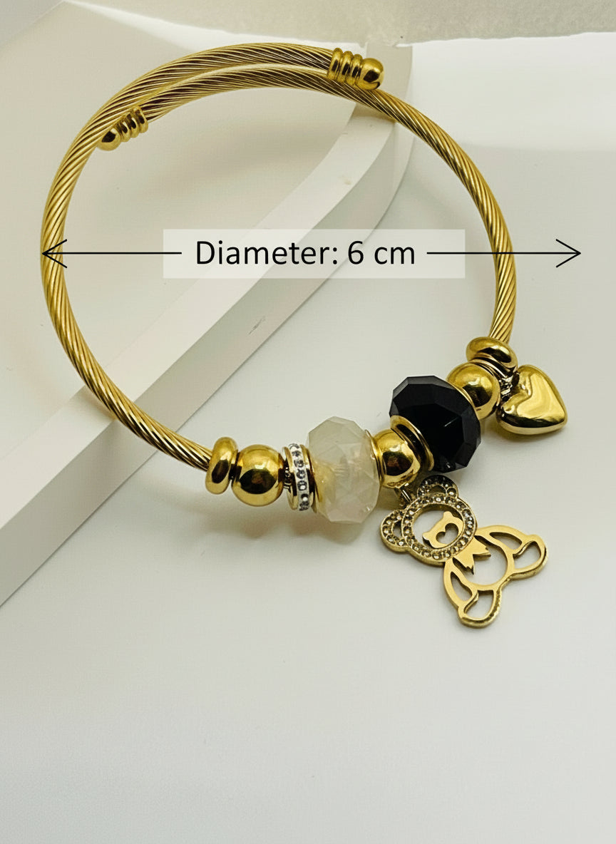 Gold bracelet with various beads and charms on a white surface