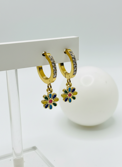 Gold hoop earrings with floral charms on a white surface