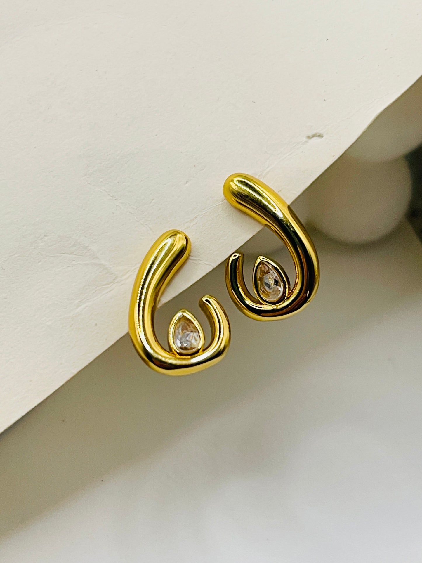 Gold earrings with diamond-like stones on a light background