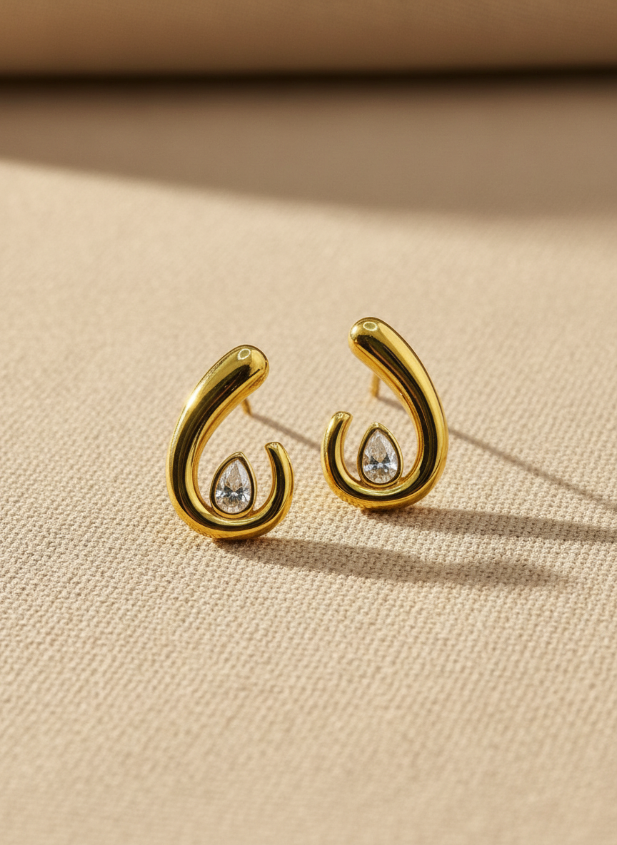 Gold earrings with gemstones on a beige fabric background